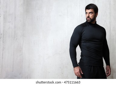 Bearded athlete black blank T-shirt with long sleeves standing on cement wall background with free space on the left - Powered by Shutterstock