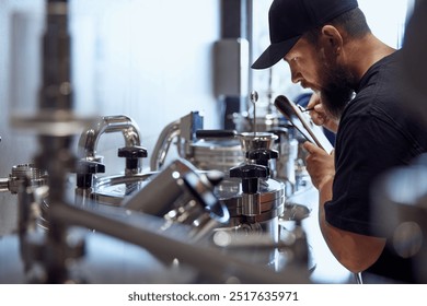 Bearded brewery technologist, focused man inspecting stainless steel brewing equipment, taking notes on clipboard. Craftsmanship of beer production. Beer, brewery, manufacture, quality control concept - Powered by Shutterstock