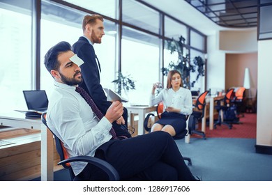 Bearded brunette with a sticker on his forehead idle in the office. Man holding a paper airplane - Shutterstock ID 1286917606