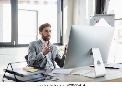 Bearded businessman having video call on computer near newspaper and notebook in office - Shutterstock ID 2090727454