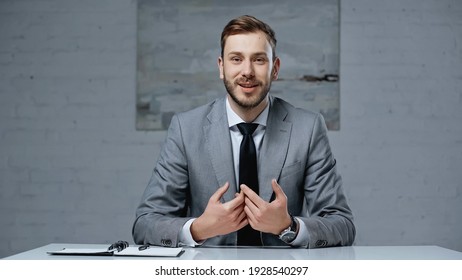 Bearded Businessman In Suit Talking While Looking At Camera In Office