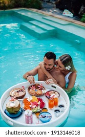 Bearded Caucasian Man Enjoys Asian Food And Swims In Pool With His Beautiful Wife She Hugs Him.