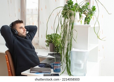 Bearded Caucasian man, Quiet quitting,  doing only what is expected or the bare minimum of job requirements. Man relaxing at work place with green potted plants.