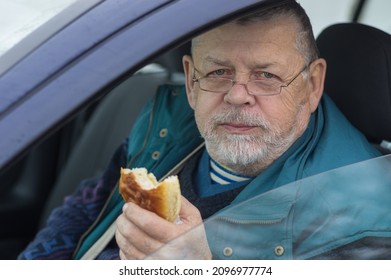 Bearded Caucasian Senior Driver Taking Patty And Looking In Camera While Sitting Inside His Car 