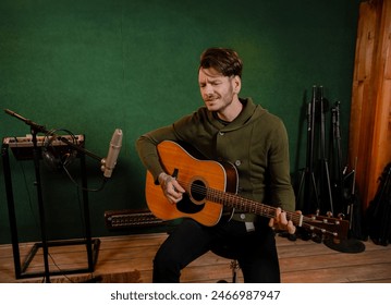 Bearded charismatic guy playing acoustic guitar in the music studio - Powered by Shutterstock