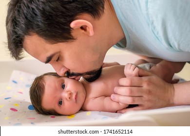 Bearded Dad Kissing Little Newborn Daughter. Baby Is Looking At Camera With Funny Surprised Face. Tenderness, Happy Family, Parental Love And Father And Infant Child Spending Time Together