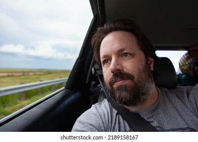 A Bearded Dad Looks Out The Window Of A Car On A Road Trip On Summer Vacation.  Lifestyle Image Of A Candid Moment Of This Middle Aged Man.