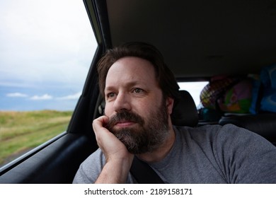 A Bearded Dad Looks Out The Window Of A Car On A Road Trip On Summer Vacation.  Lifestyle Image Of A Candid Moment Of This Middle Aged Man.