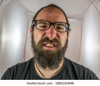 A bearded and disgusted looking man with black glasses