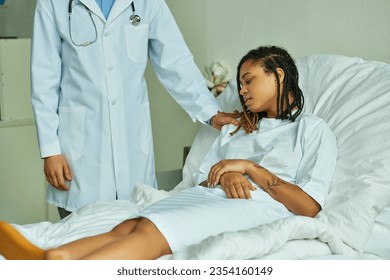 bearded doctor calming down african american woman in hospital gown, private ward, patient - Powered by Shutterstock