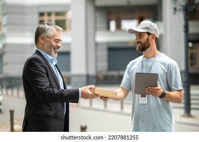 Bearded elegant businessman taking the box from a courrier