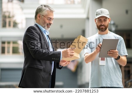 Bearded elegant businessman taking the box from a courrier