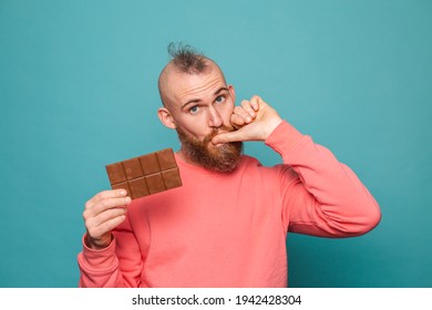 Bearded European Man In Casual Peach Isolated On Turquoise Background Holding Delicious  Chocolate Licking Fingers Copy Space