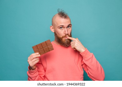 Bearded European Man In Casual Peach Isolated On Turquoise Background Holding Delicious  Chocolate Licking Fingers Copy Space