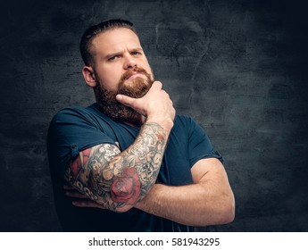 Bearded fat male with tattoo on arms posing over grey background.
