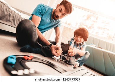 Bearded Father and Son Playing with Toy Race Road. Man Sitting on Floor. White Carpet in Room. Toy Cars. Exited Boy. Happy Family Concept. White Carpet. Lying on Floor. Indoor Fun. - Powered by Shutterstock