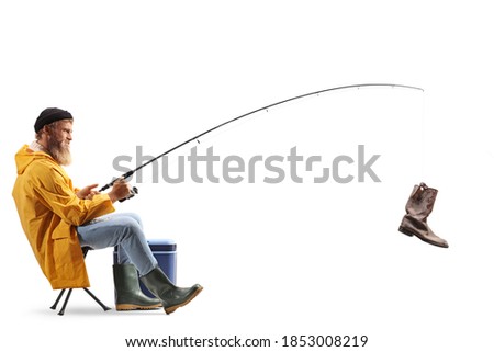 Bearded fisherman on a chair catching an old boot with a fishing rod isolated on white background