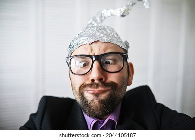 Bearded funny man in cap of aluminum foil. Concept art phobias. Conspiracy theory. Conspiracy. Insanity.