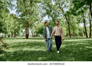 A bearded gay couple walks hand-in-hand through a lush green park, enjoying a sunny day together. - Powered by Shutterstock