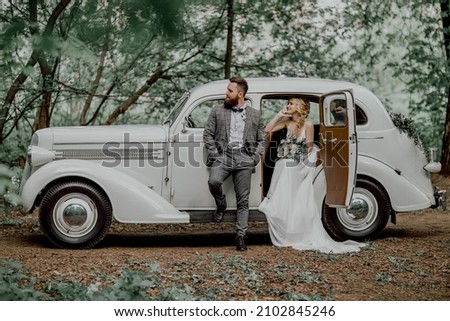 The bearded groom and beautiful bride. Retro car.