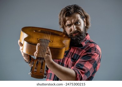 Bearded guitarist plays in a plaid shirt. Play the guitar. Guitars and strings. Bearded man playing guitar, holding an acoustic guitar in his hands. Music concept - Powered by Shutterstock