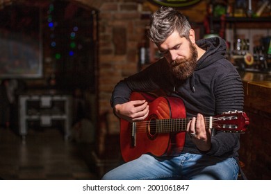 Bearded guitarist plays. Play the guitar. Beard hipster man sitting in a pub. Live music. Guitars and strings. Bearded man playing guitar, holding an acoustic guitar in his hands. Music concept. - Powered by Shutterstock