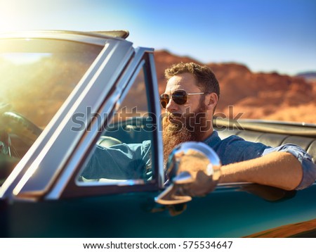 bearded guy in desert sitting in cool vintage car shot with lens lens