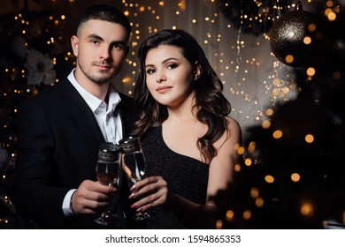 A bearded guy with a girl is celebrating Christmas. A loving couple enjoy each other on New Year's Eve. New Year's love story. Gorgeous young woman with perfect makeup and hair style in luxury dress  - Shutterstock ID 1594865353