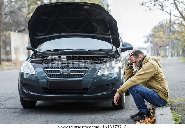 Bearded guy is repairing a car on the road, a car
broke down on a trip