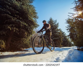 A Bearded Guy Rides A Bike In The Winter In The Park. Active Pastime In Winter. Bicycle As An Ecological Transport