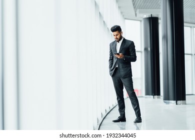 Bearded Handsome Indian Man In The Middle Of A Modern Building, A Solid Man In A Suit, He Talks On The Phone, A Business Meeting.