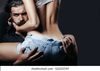 bearded handsome man and female slim flexible body of young pretty woman or girl with sexy buttocks in jeans shorts on grey background