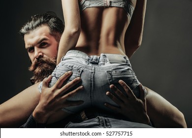 Bearded Handsome Man And Female Slim Flexible Body Of Young Pretty Woman Or Girl With Sexy Buttocks In Jeans Shorts On Grey Background