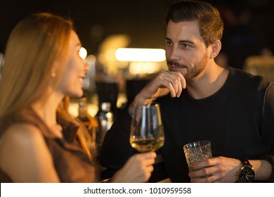 Bearded handsome man smiling thoughtfully listening to his beautiful woman talking while enjoying drinks together at the bar copyspace flirting dating romantic seduction couples communication
