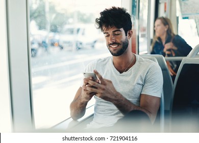 Bearded Hipster Guy Is Reading Emails On A Display Of A Smartphone Connected To Public Wi-fi While Sitting In A City Bus. Handsome Male Is Looking At The Screen Of A Mobile Phone While Texting.