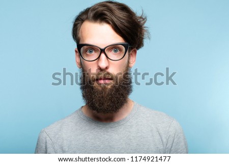 bearded hipster guy wearing cat eye glasses. stylish modern fashionist. portrait of a geeky quirky eccentric man on blue background.