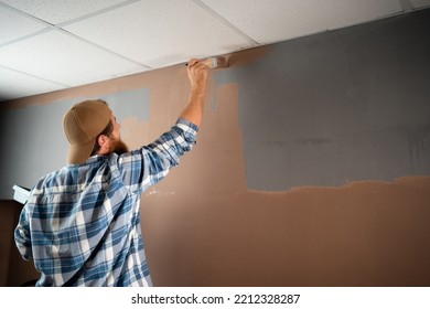 Bearded House Painter Painting House Wall Near Ceiling With Painting Brush. Copy Space, Advertising Or Your Design.