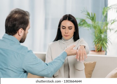 bearded hypnotist holding wrist of young woman with closed eyes during hypnotherapy - Powered by Shutterstock