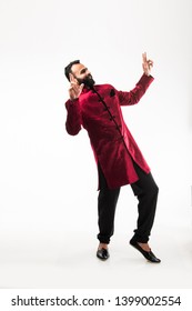 Bearded Indian Man Performing Desi Dance Steps While Wearing Traditional Kurta/sherwani, Celebrating Wedding Or Party, Isolated Over White Background