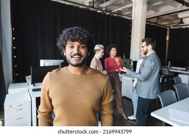 Bearded Indian Man Smiling At Camera Near Colleagues Talking In Ad Agency