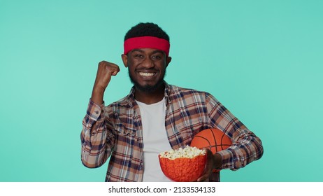 Bearded Joyful Young African American Man 20s Sportsman Alone Basketball Fan In Shirt Holding Ball Doing Winner Gesture, Dancing Isolated On Blue Background. Workout Sport Motivation Lifestyle Concept