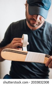 Bearded male ice hockey player wraps tape around hook hockey sticks to protect against impact and damage - preparing for a hockey game - Shutterstock ID 2033832308
