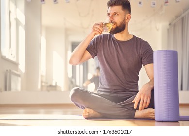 Bearded Male Sitting On The Floor Near Foam Roller And Enjoying Hot Drink