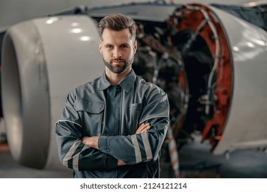 Bearded man aircraft maintenance technician looking at camera and smiling while keeping arms crossed