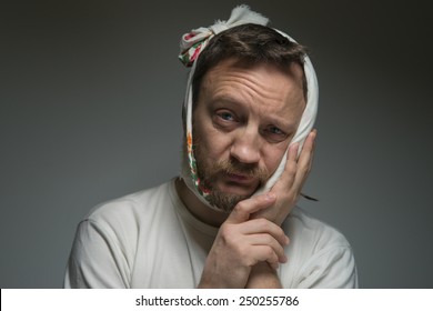 A bearded man with a bandage on his face. He has a toothache.