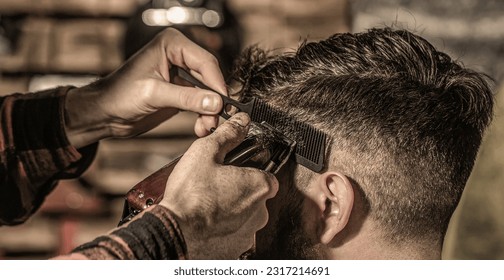 Bearded man in barbershop. Haircut concept. Man visiting hairstylist in barbershop. Barber works with hair clipper. - Powered by Shutterstock