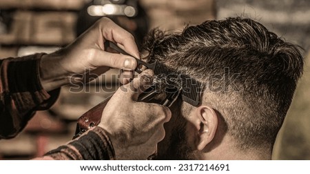 Bearded man in barbershop. Haircut concept. Man visiting hairstylist in barbershop. Barber works with hair clipper.