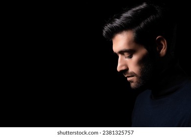 Bearded man bend down the head in dark room Guy looks down on black background with side view Concept serious depression and dismal Alone businessman close eyes and hopeless depressed He get lonely