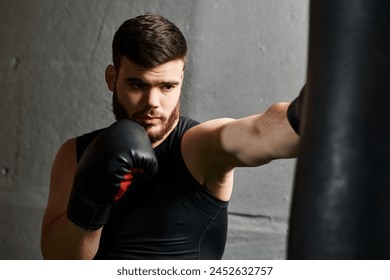 A bearded man in a black shirt and boxing gloves throws punches at a punching bag in a gym. - Powered by Shutterstock