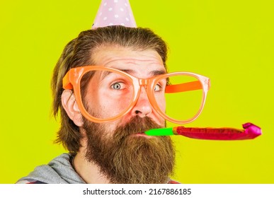 Bearded Man Blowing Noisemaker. Birthday Celebration. Party Time. Guy In Cone Hat And Big Glasses.